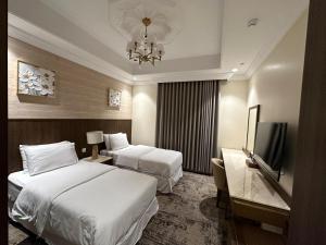 Una habitación de hotel con dos camas y un televisor de pantalla plana. en شقق جوين المخدومة- اقتصادي, en Yeda
