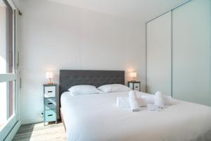 une chambre avec un grand lit blanc avec deux serviettes blanches dans l'établissement Le Nid de Men Er Beleg - Appt proche plage, à Saint-Philibert