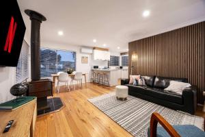 a living room with a black couch and a kitchen at The Eighth - Pet Friendly in Rosebud