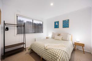 a white bedroom with a bed and a window at The Eighth - Pet Friendly in Rosebud
