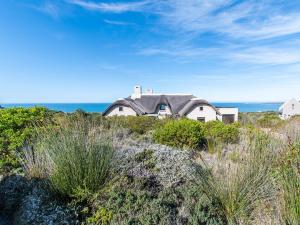 a house on top of a hill near the ocean at Elysian Bay Cottage in Boggomsbaai