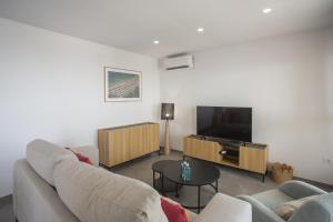 un salon avec un canapé et une télévision à écran plat dans l'établissement AT Ponent V, à La Playa de la Torre de Piles