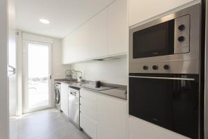 une cuisine avec des armoires blanches et un appareil noir dans l'établissement AT Ponent V, à La Playa de la Torre de Piles