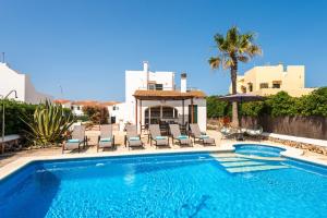 a swimming pool with chairs and a house at Brisa Marina in Cala en Blanes