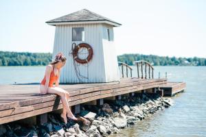 a woman sitting on a dock next to a lighthouse at Hotel Haikko Manor & Spa in Porvoo