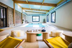 an indoor pool with a table and chairs in a room at L'Escapade d'Acquigny, Piscine, Foot Five, Salle de sport, BabyFoot in Acquigny