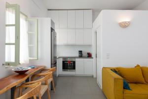 a kitchen and living room with a yellow couch and a table at Sifnos Hideaway in Sifnos