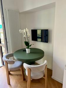 einen grünen Tisch mit zwei Stühlen und eine Vase mit Blumen in der Unterkunft Casa Vicina INALPI ARENA in Turin