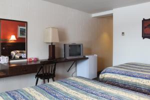 a hotel room with two beds and a desk with a television at Auberge - Motel Le Pigeonnier in Farnham