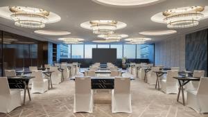una sala conferenze con tavoli, sedie e uno schermo di InterContinental Hotels Zhengzhou Zhengdong a Zhengzhou