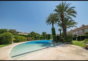 a swimming pool in a yard with two palm trees at Ático sagaro in Sant Feliu de Guixols