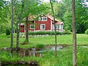 a red house in the middle of a field with trees at Vallevägen Country Retreat - Private Pond, Fireplace & Nature 