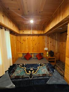 Wilderness Cottages and camps kasol في كاسول: غرفة نوم مع سرير في غرفة خشبية