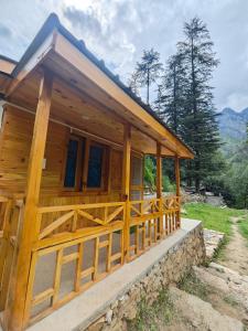 Wilderness Cottages and camps kasol في كاسول: منزل خشبي مع شرفة كبيرة