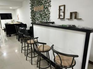 Un bar con taburetes negros en una sala con peluquería. en 9 Bedrooms house, en Medellín