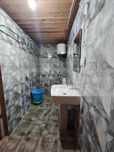 Wilderness Cottages and camps kasol في كاسول: حمام مع حوض وجدار حجري