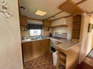 a small kitchen with wooden cabinets and a sink at Caravan in Banff