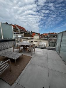 a patio with a table and benches on a balcony at Appartement Knokke - 2 Chambres in Knokke-Heist +2 photos