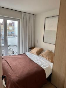 a bedroom with a bed and a large window at Appartement Knokke - 2 Chambres in Knokke-Heist