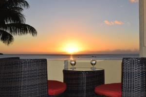 een zonsondergang op het strand met twee stoelen en een tafel bij Baywatch Apartment in La Gaulette