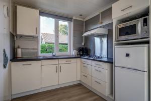 eine Küche mit weißen Schränken und einem Fenster in der Unterkunft Vakantiehuis De Strandloper - Julianadorp aan Zee in Julianadorp