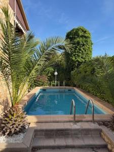 Una piscina con escaleras y palmeras junto a un edificio. en Villa Penedes, en Roda de Bará