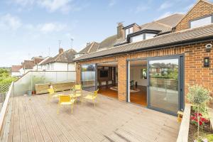 un patio con mesa y sillas en una terraza de madera en Homestay, en Hendon