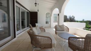 eine Veranda mit Stühlen, einem Sofa und einem Tisch in der Unterkunft Villa en primera linea de mar cerca de Binibeca in Sant Lluís + 18 Fotos