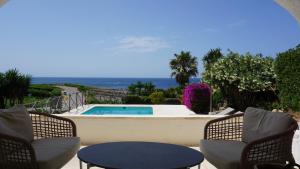 eine Terrasse mit Pool, Stühlen und einem Tisch in der Unterkunft Villa en primera linea de mar cerca de Binibeca in Sant Lluís