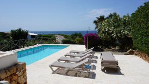 eine Gruppe von Liegestühlen neben einem Swimmingpool in der Unterkunft Villa en primera linea de mar cerca de Binibeca in Sant Lluís