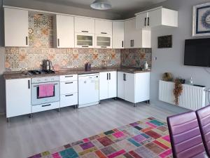 a kitchen with white cabinets and a colorful rug at Begonvil Butik Apart in Eceabat