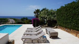 eine Gruppe von Liegestühlen neben einem Swimmingpool in der Unterkunft Villa en primera linea de mar cerca de Binibeca in Sant Lluís
