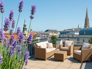 a patio with chairs and purple flowers on a balcony at MyPlace Premium Apartments in Vienna