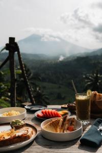 a table topped with plates of food and a drink at Veluvana Mountain in Sidemen