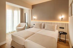 a bedroom with a large white bed and a chair at Vita Home Lanzarote I Deluxe Apartments in Arrecife