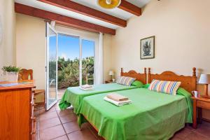 una camera con un letto verde e una grande finestra di Villa Bini Cinco by Villa Plus a Binibeca