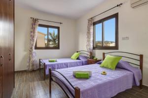 two beds in a room with two windows at Villa Kassiopeia by Villa Plus in Peyia
