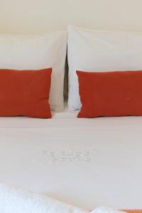 a white bed with two red pillows on it at Invictus Escape – Jacuzzi & Charm in the City in Porto