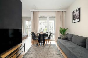 Una sala de estar con un sofá y una mesa con sillas. en Modern Studio with Parking near Lake Malta by Noclegi Renters, en Poznan