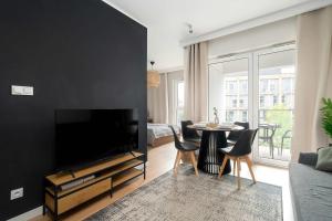 Una sala de estar con un televisor grande y una mesa. en Modern Studio with Parking near Lake Malta by Noclegi Renters, en Poznan