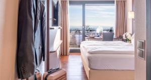 a hotel room with a bed and a balcony at PLAZA Hotel Föhr am Bodensee in Friedrichshafen