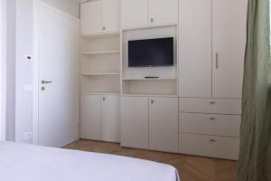 a white bedroom with a tv and white cabinets at Il cubo di Aligi in Missaglia
