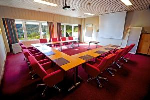 a conference room with a long table and red chairs at Moi Hotel in Moi