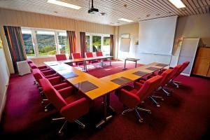 una sala de conferencias con una mesa larga y sillas rojas en Moi Hotel, en Moi
