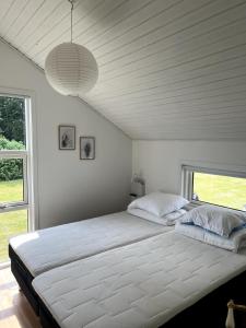 a bedroom with a large white bed with a large window at Cozy holiday home - spa, hot tub and play room - close to Marielyst square in Marielyst +22 photos