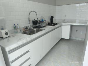 a white kitchen with a sink and a stove at Apto Lindo e Aconchegante 3 in Manaus