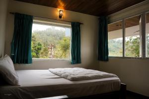a bedroom with a bed and a window with green curtains at 11 Haven Street Kodaikanal in Kodaikānāl