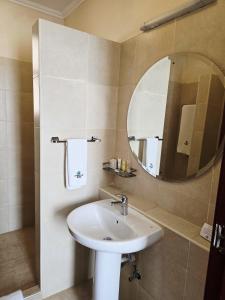 a bathroom with a sink and a mirror at Vittoria Suites Milimani, Kisumu in Kisumu