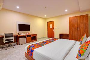 a bedroom with a bed and a desk with a television at FabHotel Millennials in Bengaluru