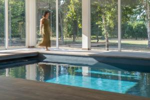 a woman walking by a swimming pool in a building at Quinta do Areal in Lousã